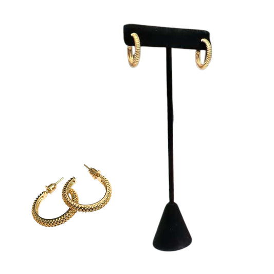 Gold hoop earrings on a black velvet stand with additional earrings on a white background