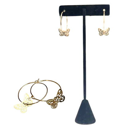 Gold butterfly earrings on a black T-shaped stand with a gold hoop earring in front.