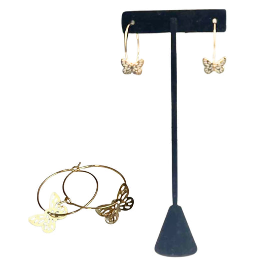 Gold butterfly earrings on a black T-shaped stand with a gold hoop earring in front.
