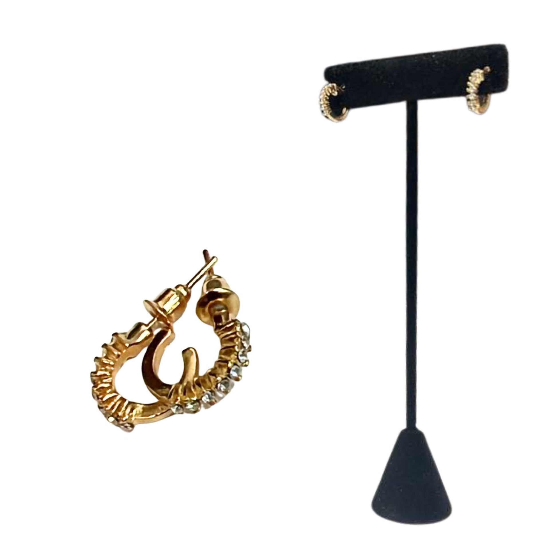 Gold hoop earrings on a black earring stand against a white background