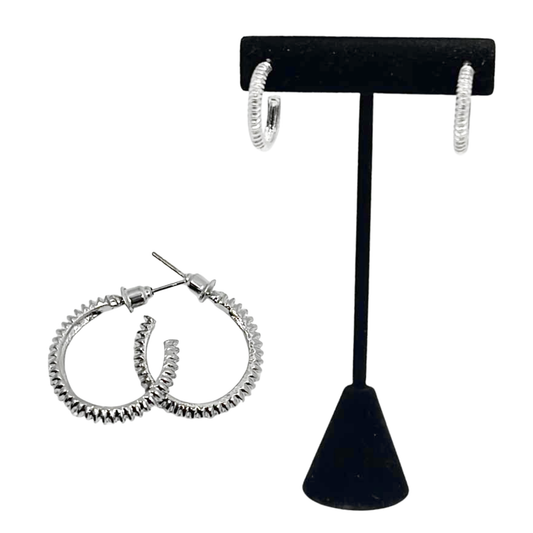 Silver hoop earrings on a black earring stand against a white background