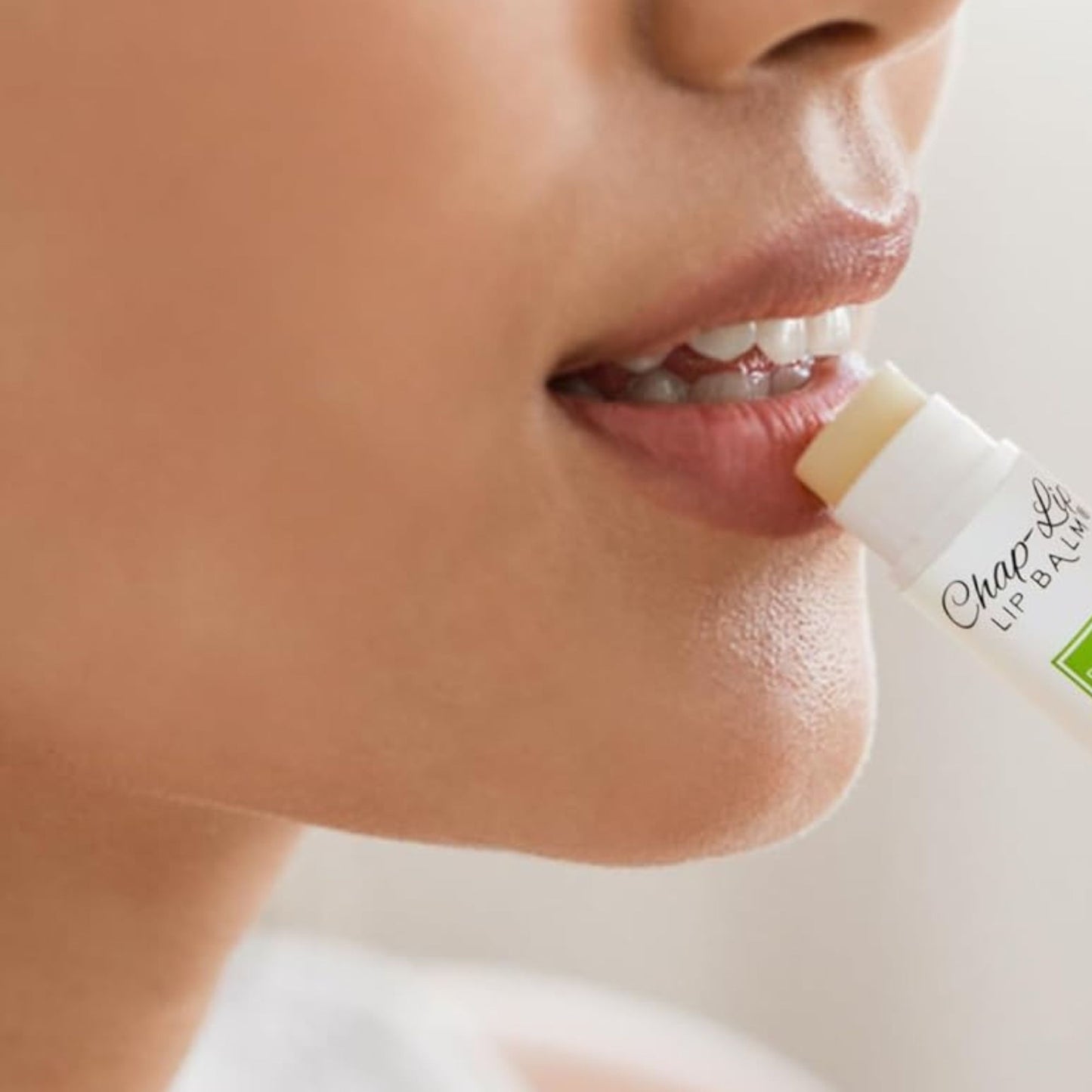 Person applying lip balm to their lips with a focus on the product.