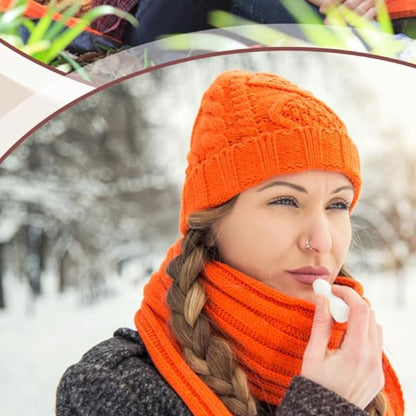 Woman in orange knit hat and scarf applying lip balm outdoors in winter