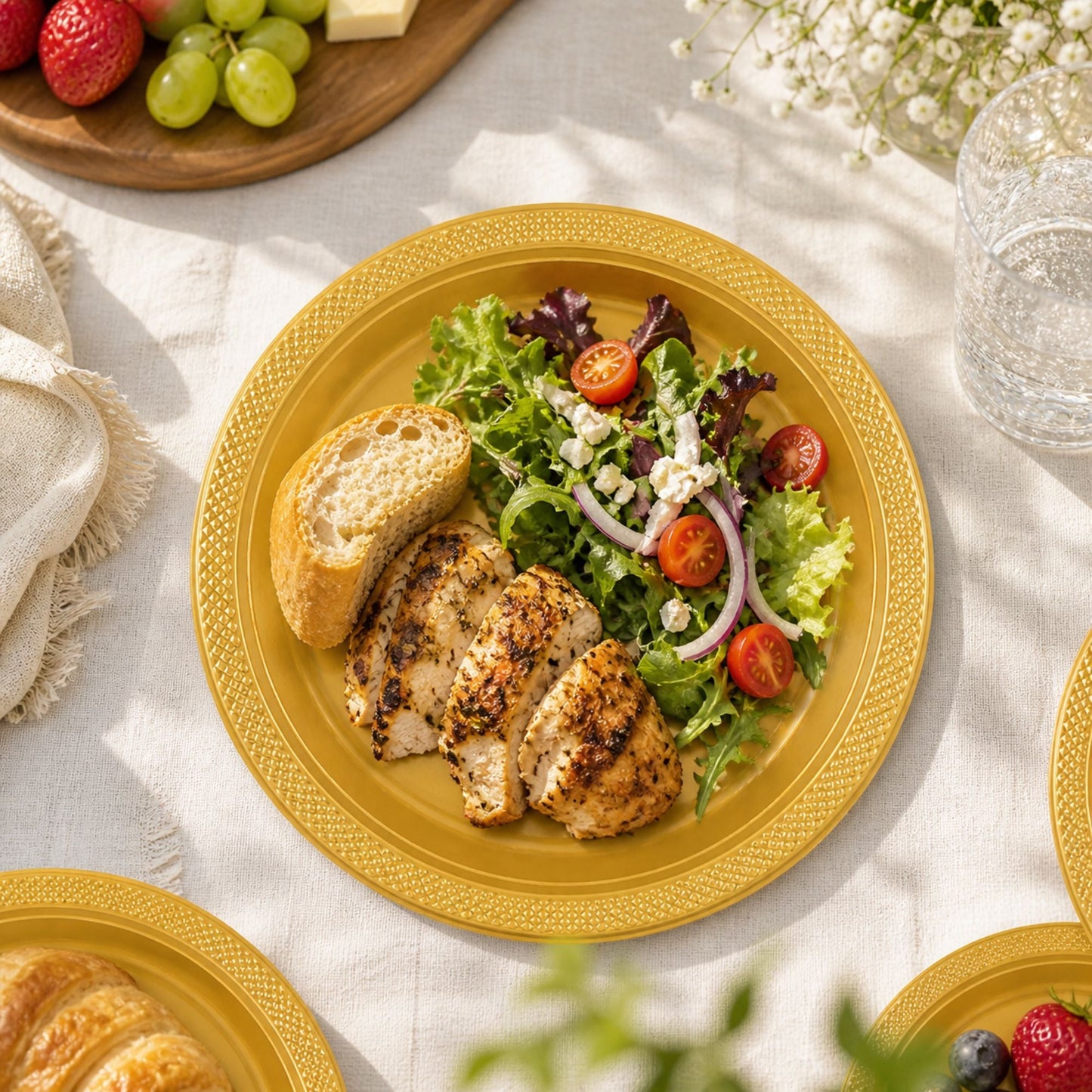 Yellow plate with chicken, salad, and bread on a light fabric tablecloth.
