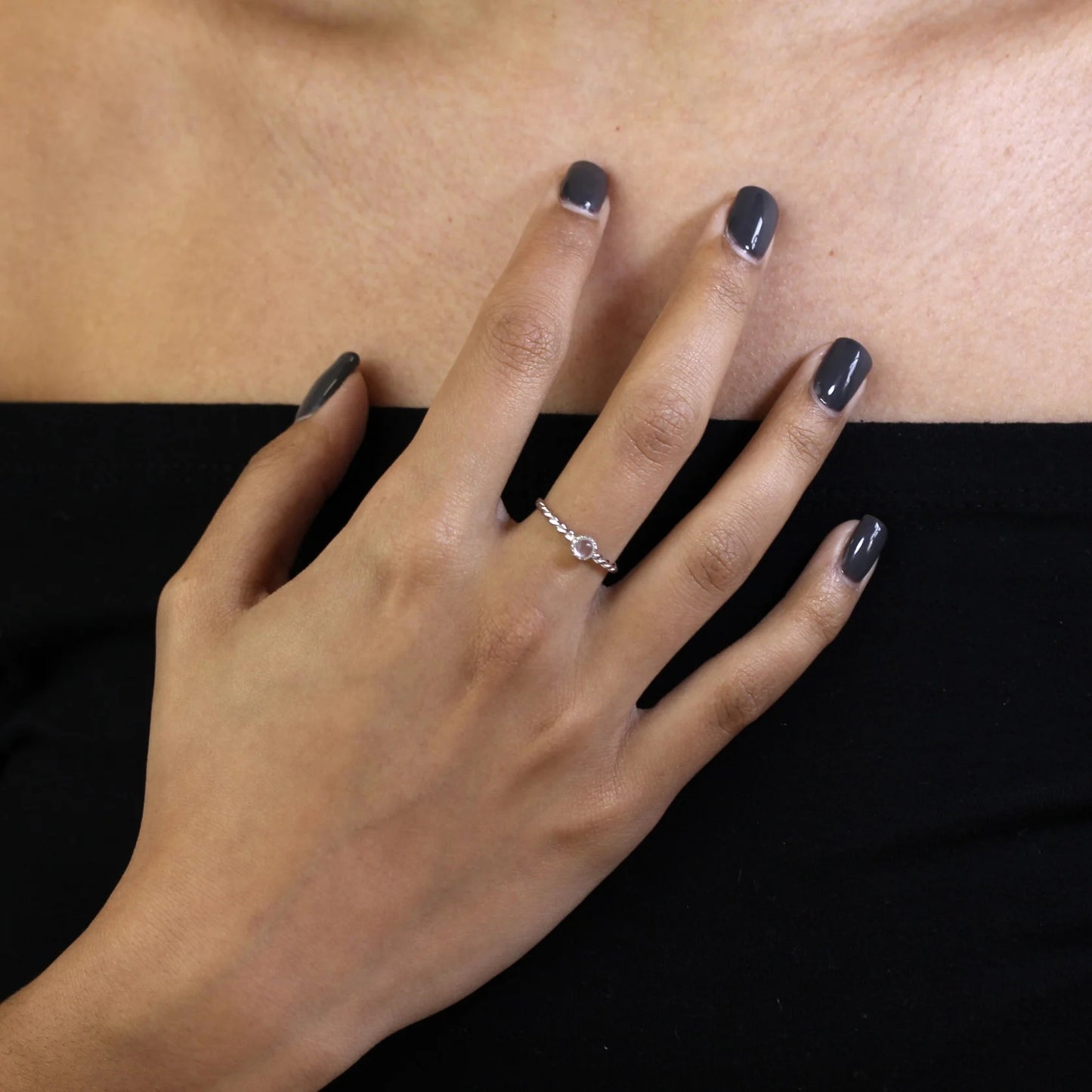 Hand with a silver ring on a black and beige background