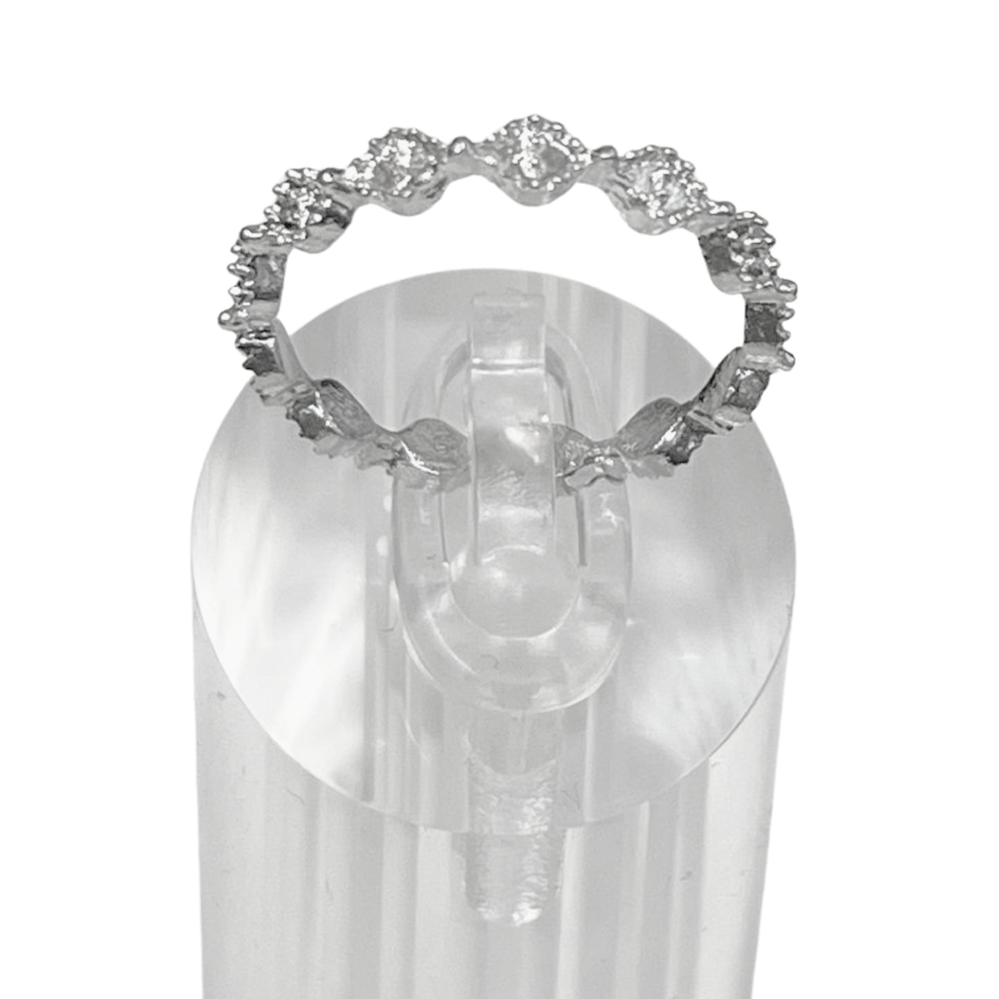 Silver ring with gemstones on a clear stand against a white background
