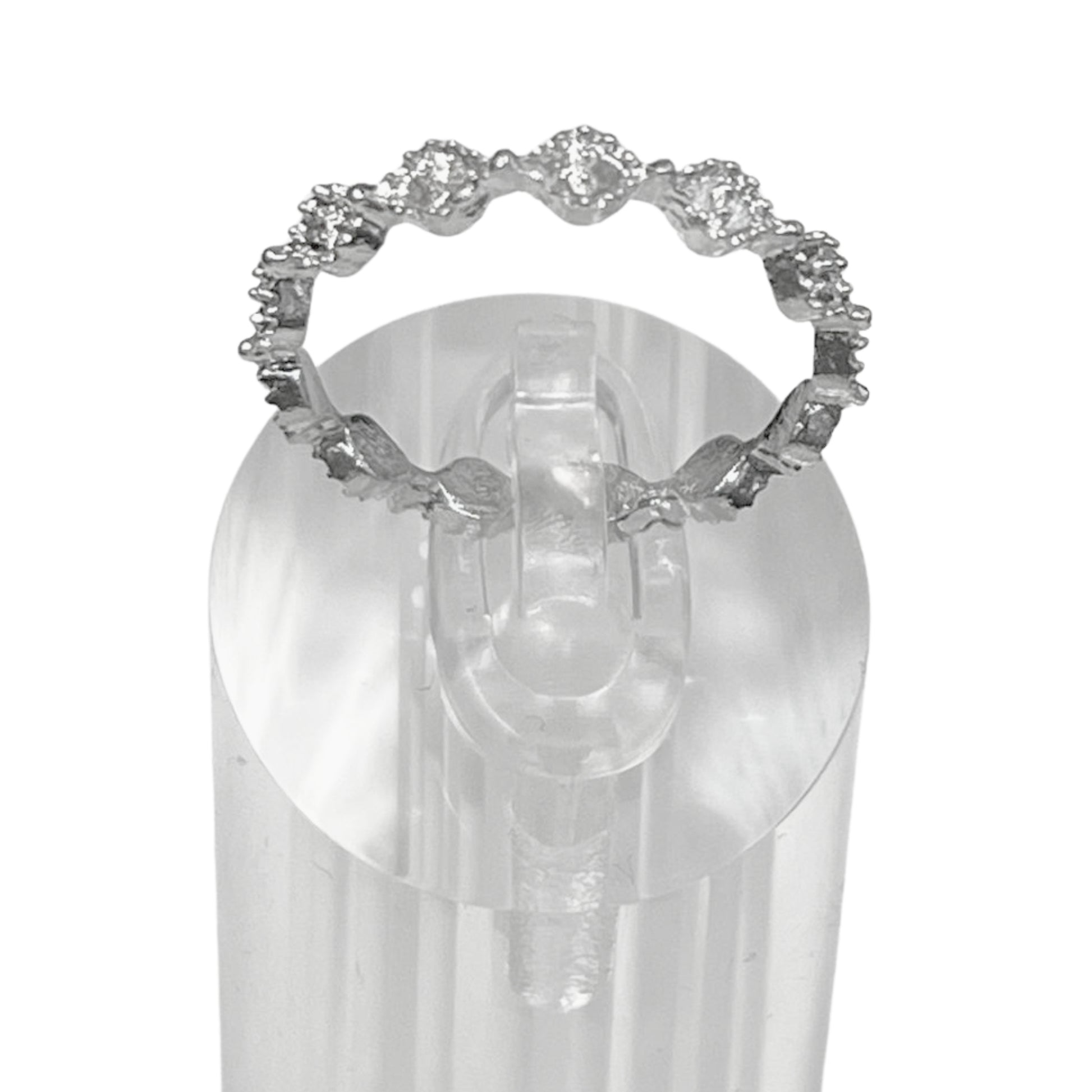 Silver ring with gemstones on a clear stand against a white background