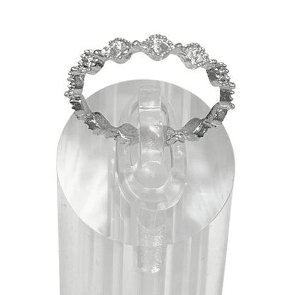 Silver ring with gemstones on a clear stand against a white background