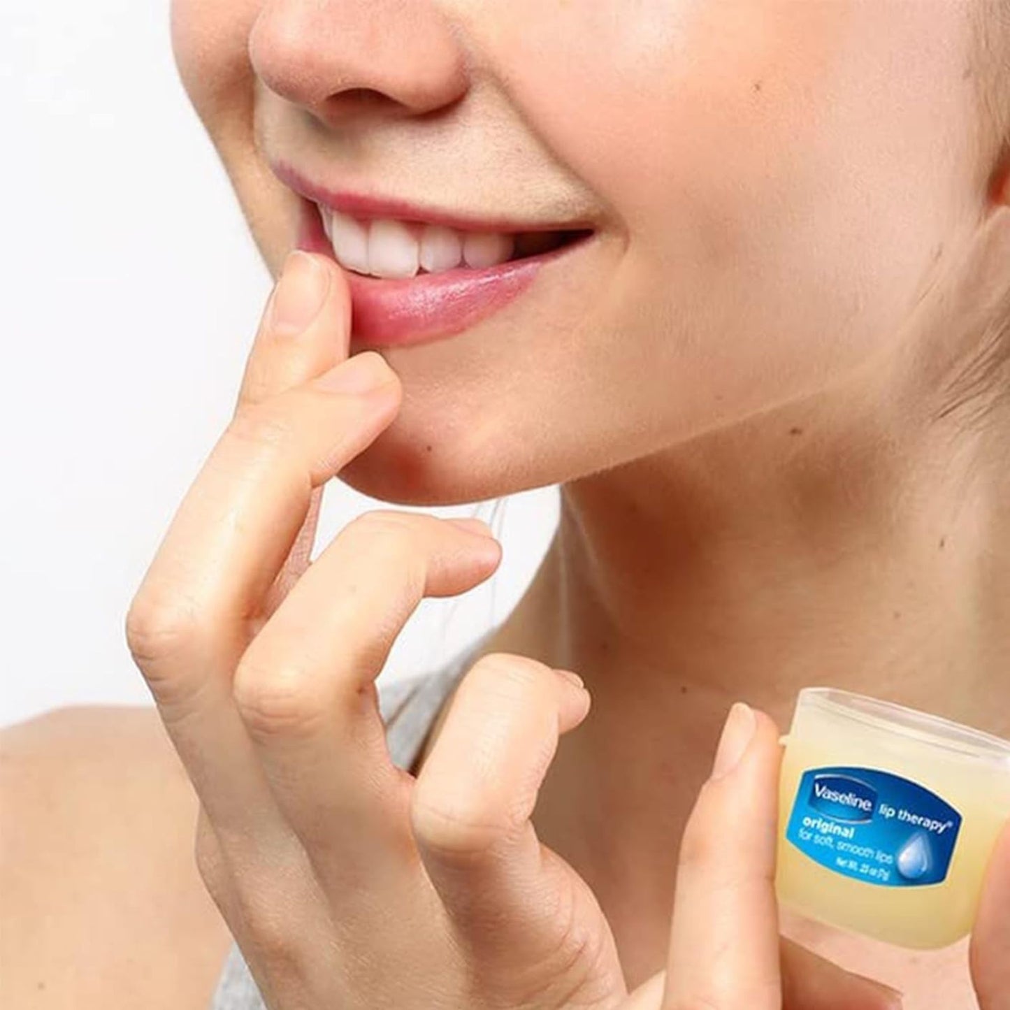 Person applying Vaseline lip balm to their lips with a close-up of the product.