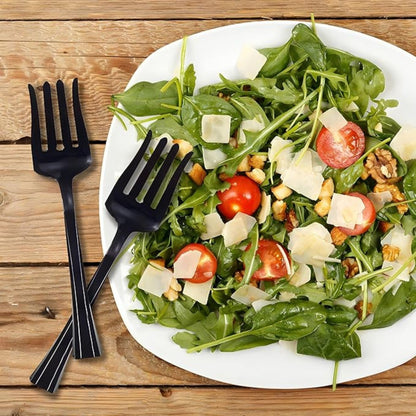 Plated salad with black utensils on a wooden surface